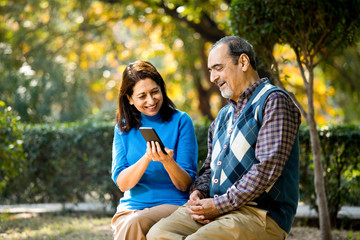 Fototapeta premium Senior woman sharing media content with her husband using mobile phone