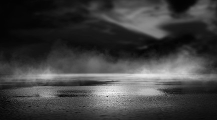 Dramatic black and white background. Cloudy night sky, moonlight, reflection on the pavement. Smoke and fog on a dark street at night.