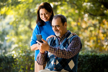 Senior woman sharing media content with her husband using mobile phone
