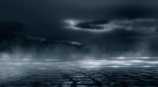 Dramatic black and white background. Cloudy night sky, moonlight, reflection on the pavement. Smoke and fog on a dark street at night. © MiaStendal
