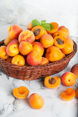 ripe apricots in a basket with daisies on a light background