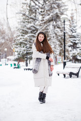 Fototapeta na wymiar Young brunette woman in white down jacket in winter street