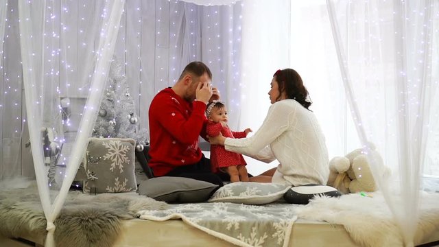 Happy family playing together: mother, father and 1 year old baby girl. Christmas holiday