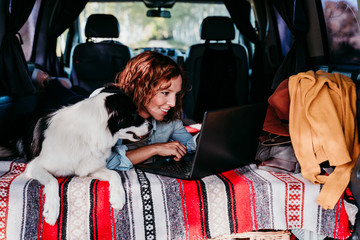 woman and border collie dog in a van. woman working on laptop. Travel concept