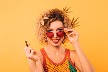 Rastafarian woman with marijuana leaves with her hair and stylish glasses holds a pipe for smoking...