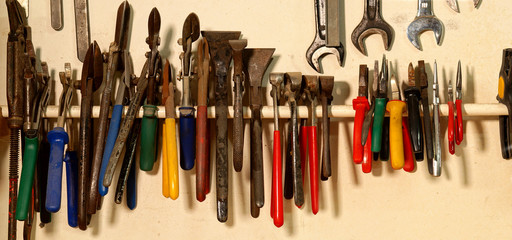 panoramic view of Tongs. Pliers hang on nails on the banner canvas. pincers, Hand Tools in the workshop on wooden wall. Panorama Working tools. Repair and construction tools collection.