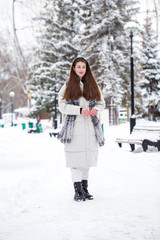 Fototapeta na wymiar Young brunette woman in white down jacket in winter street