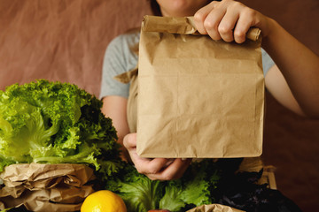 Organic vegetables in eco bag in market. Woman seller giving craft paper bag with products in organic food store.  Healthy nutrition, Zero Waste, Lifestyle Concept. Banner for for web, design. Mock up