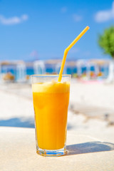 Healthy fresh orange juice on the sunny beach. Vacation concept. Summer holidays. 