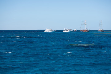 Dark-blue and wavy surface of the Red Sea with ships in the distance