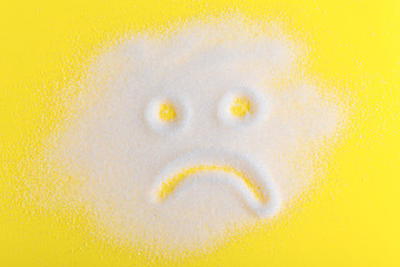 Salt scattered on black surface. Drawn sad face. Concept- diet, harm to health from excessive...