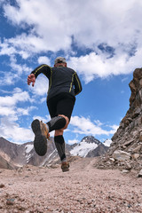 Closeup of feet with running shoes of a trailrunner man running in the mountains trail