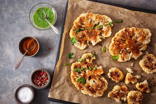 cauliflower steaks with herb and spice on baking tray. plant based meat substitute