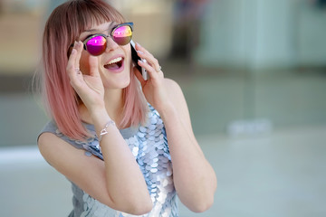 Close up of a woman in pink sunglasses talking on the phone in the street.