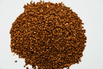 a handful of buckwheat sprinkled with a hill on a white background