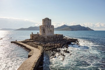 Methoni Castle with a stone bridge in sunny weather during early morning hours with water waves in Greece