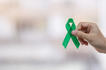 Man holding green Ribbon for supporting people living and illness. Liver, Gallbladders bile duct, kidney Cancer and Lymphoma Awareness month concept
