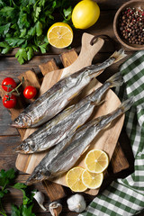 Smoked or dried smelt fish on a wooden Board on a brown wooden table. Top view with space for text	