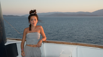 Fototapeta premium Closeup of Asian teen in striped tube top leaning against railing