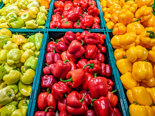 Colorful bell peppers in green, red and yellow colors stacked in market grocery store for sale as a part of a healthy vegetarian vegan diet