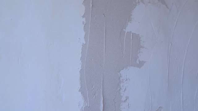 Plasterer man is spackling with putty plaster aligning wall with trowel, hands closeup. Finishing construction renovation works. Worker builder making overhaul applying plaster on wall using spatula.
