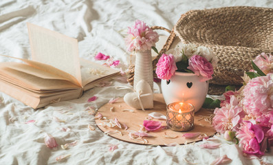 Candle and Vase with roses and peonies flowers and spring decor on the books