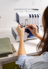 Girl threading the needle of a sewing machine.