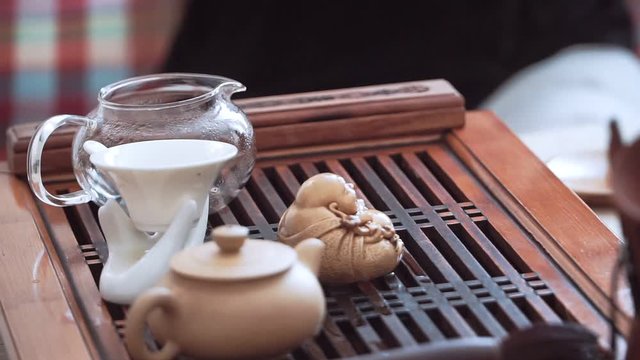 Hands of girls apart the cups of tea to the wooden table, tea ceremony