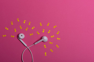 white earphones and white paper notes on orange background. view from above.