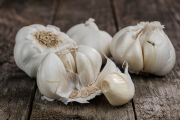 Verschiedene Knoblauch (lat. Allium sativum) auf alten, rustikalen Holz