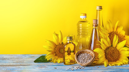 Rural still-life - sunflower oil in bottles with flowers of sunflower (Helianthus annuus), closeup