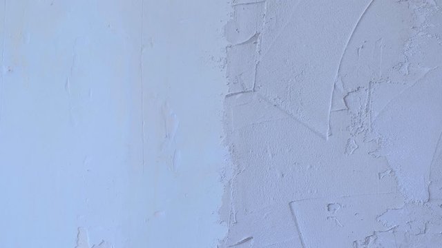Putty wall aligning with plaster in room, renovation construction works and overhaul, closeup view. Finishing repairing works. Texture of gray cement wet plaster and dry white wall.
