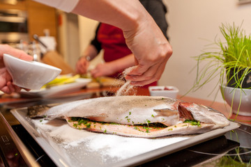 Hand streut Salz auf Fisch