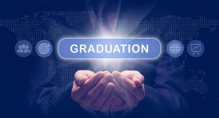 Businessmans cupped hands holding an Graduation business concept on a computerised display.