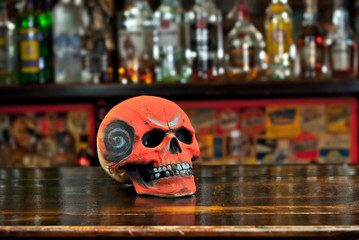 Human skull on a bar counter. Red skull on a background of bottles with alcohol. Biker Pub.