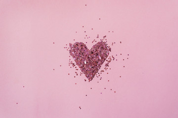 Valentine's Day concept. Heart symbol made of sparkles confetti on pink background. Flat lay, top...