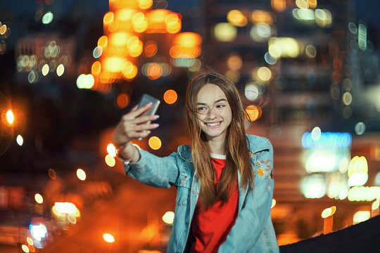 Teen girl on cityscape background making self portrait with her smart phone