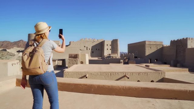 Young Foreign Female Tourist Taking Mobile Photos of Ancient Bahla Fort in Oman
