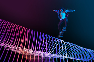 Caucasian young skateboarder riding on dark neon lighted line background. Training in action and...