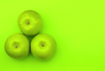 three green apples on a green background
