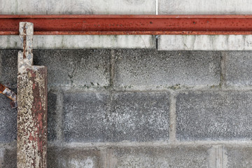 Concrete block wall background and texture with Rusted beams and columns left and top of frame.