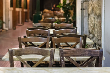 Wooden chairs and table outdoors on the street of a greek taverna.