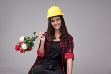 Business woman engineer portrait. Architect worker protect helmet wearing. Busy and work hard. She wear red and black table shirt.hold red and white rose bouquet in arm.