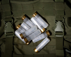 white cartridges for hunting weapons lie on a green military backpack