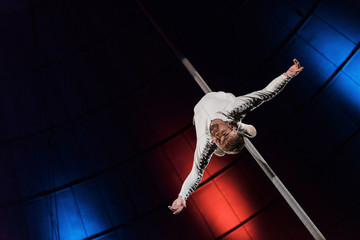 low angle view of strong acrobat with outstretched hands performing on metallic pole