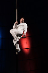 low angle view of strong acrobat holding metallic pole while performing in circus