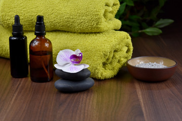 Obraz na płótnie Canvas Spa and wellness setting with cosmetic accessories stock images. Massage stones with orchid stock images. Spa-concept with zen stones, orchid flower, green towel, cosmetic bottles and salt