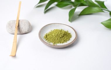 White ceramic spoon with tea of a match on a light gray background