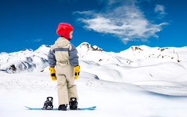 Fototapeta na wymiar Child on the slopes for the first time on a snowboard