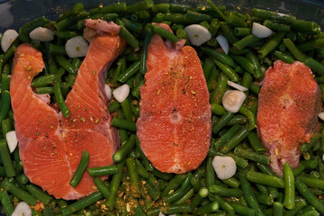 Cooking red fish steak with fresh beans, onions and garlic